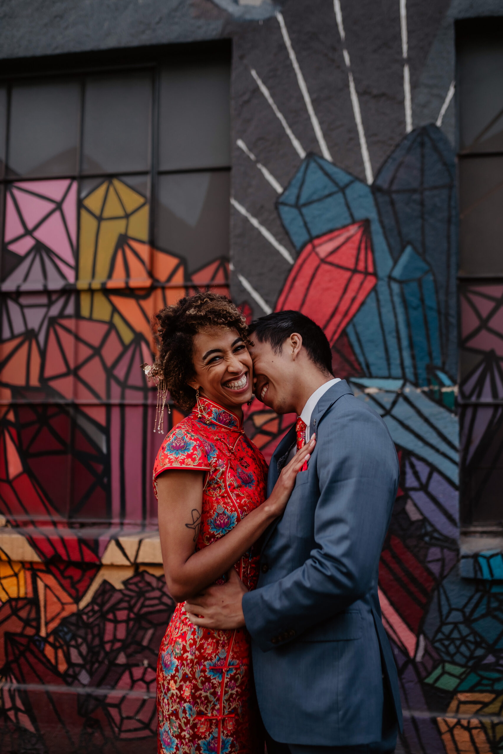 Woman laughing as man holds her in front of colorful wall in Capitol Hill
