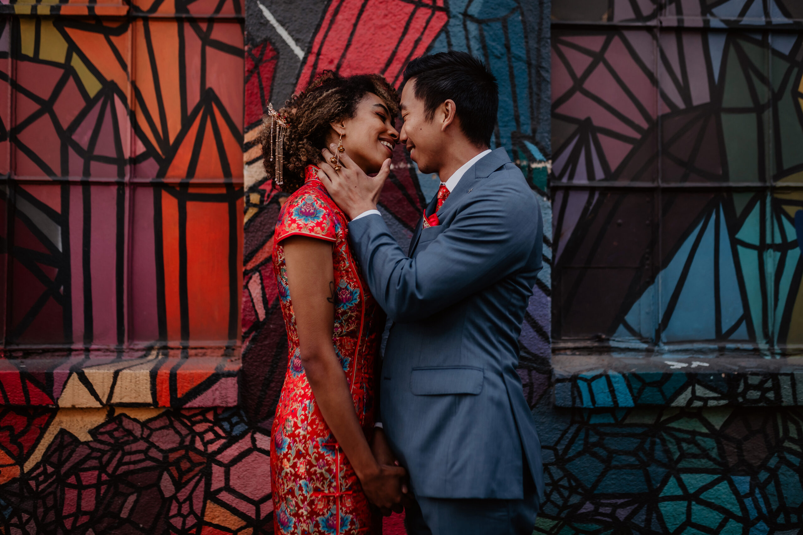 Couple embracing in front of a colorful mural in Seattle
