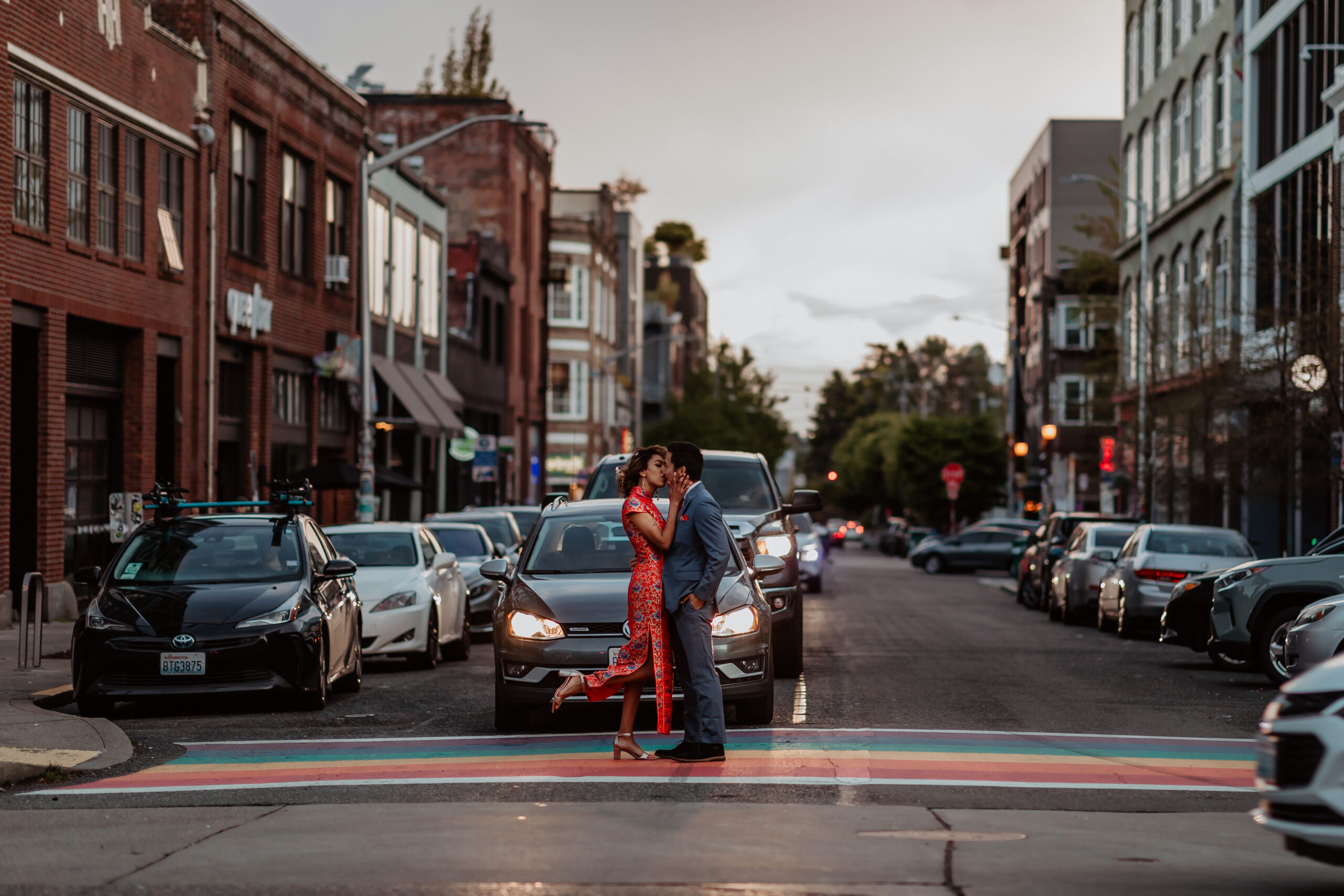 Couple wearing chinese wedding clothes kiss on rainbow crosswalk in Capitol Hill