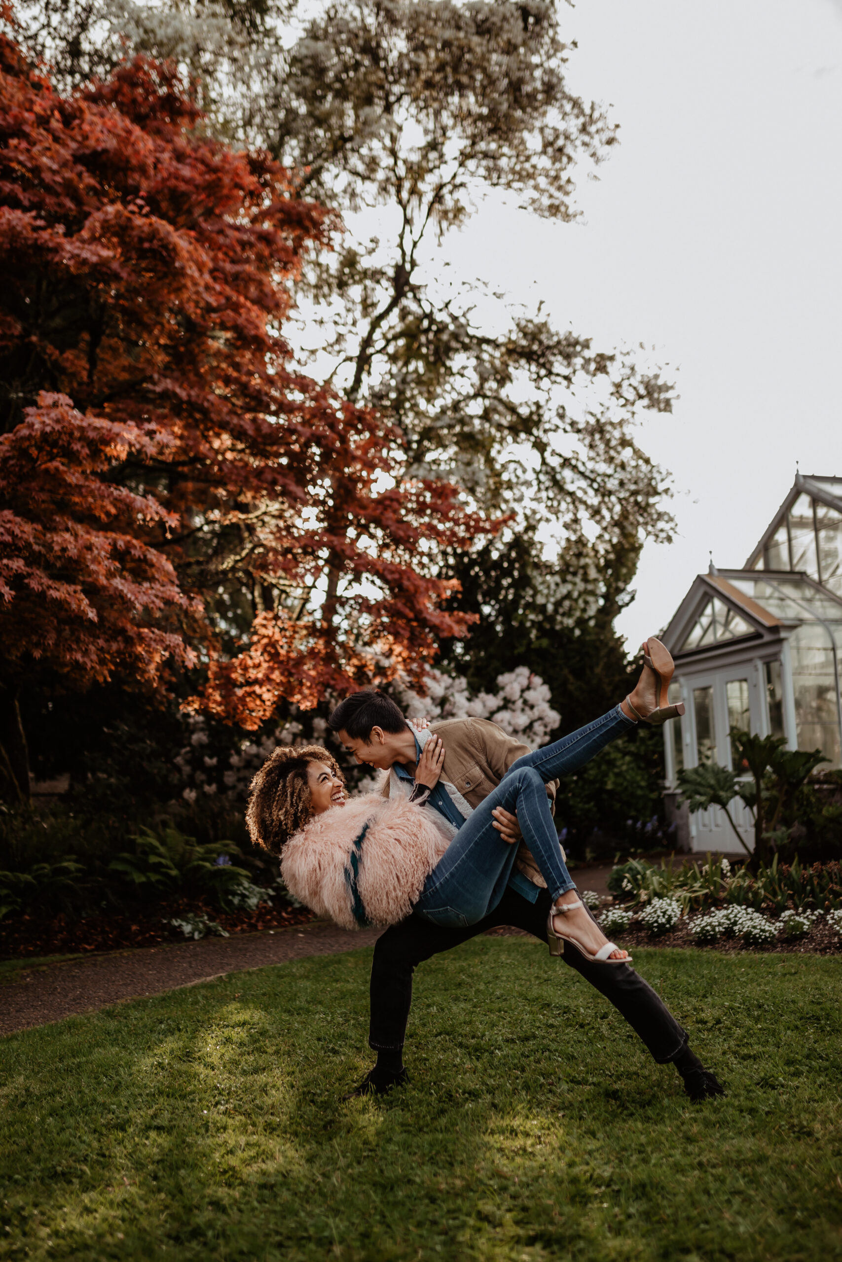 Woman being princess carried and dipped by man in front of colorful trees at Volunteer Park.
